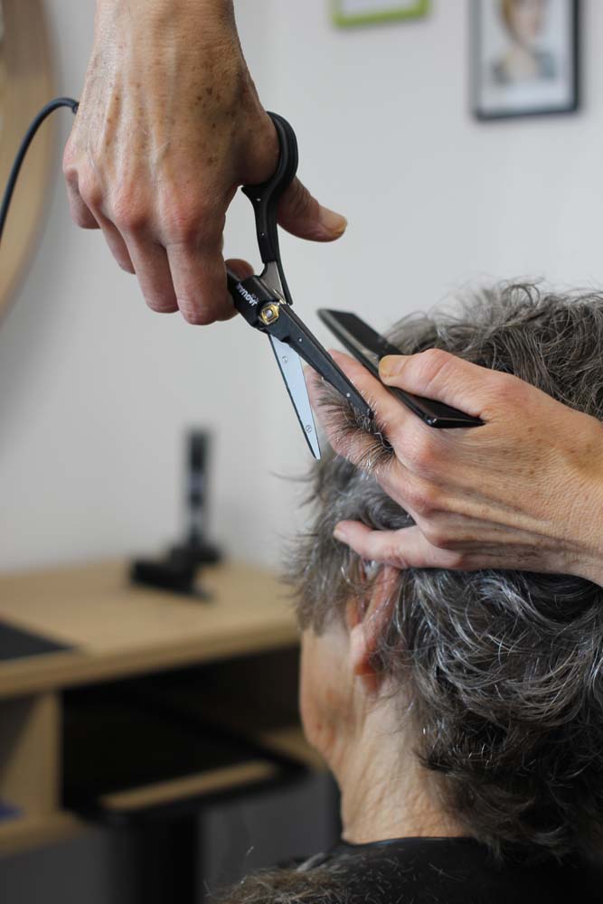 Femme senior de dos qui se fait couper les cheveux